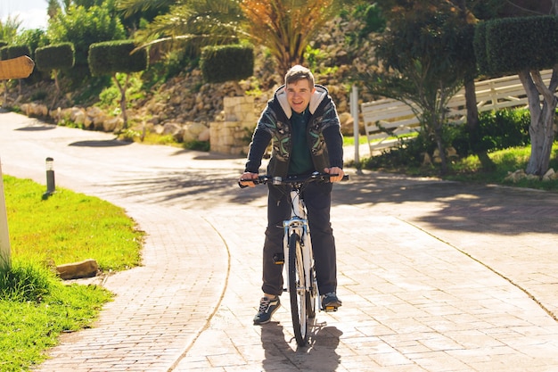 Schöner junger Mann mit Fahrrad im Park am sonnigen Tag