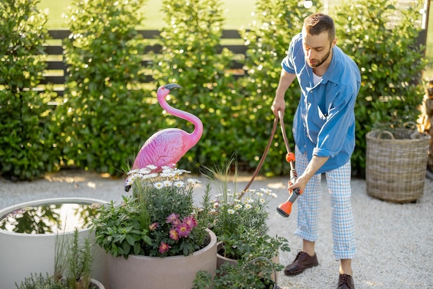 Schöner Kerl, der Blumen im Garten gießt