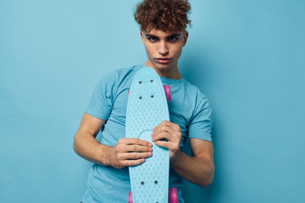 Schöner Kerl Skateboard in der Hand in blauen T-Shirts Lifestyle unverändert