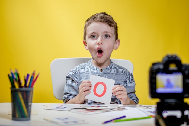 Schöner kleiner Blogger, der über das Lernen des Alphabets auf Gelb bloggt. Zurück zur Schule. Online-Fernunterricht.