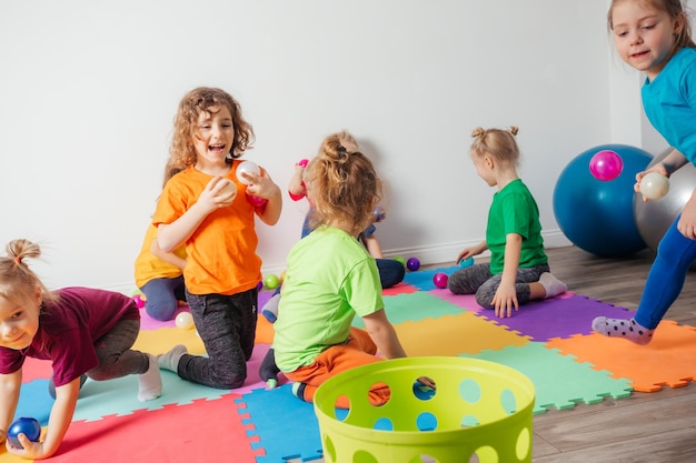 Schöner kleiner Junge, der mit kleinen Bällen und Plastikkorb spielt