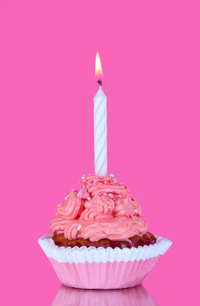 Schöner kleiner Kuchen mit Kerze auf rosa Hintergrund