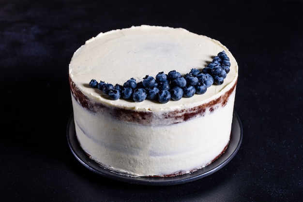 Schöner leckerer Kuchen mit weißer Sahne und Beeren der Heidelbeere