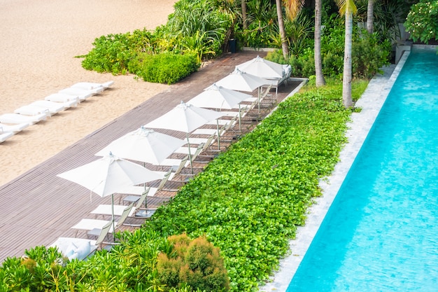 Schöner Luxusregenschirm und Stuhl um Swimmingpool im Hotel und Erholungsort