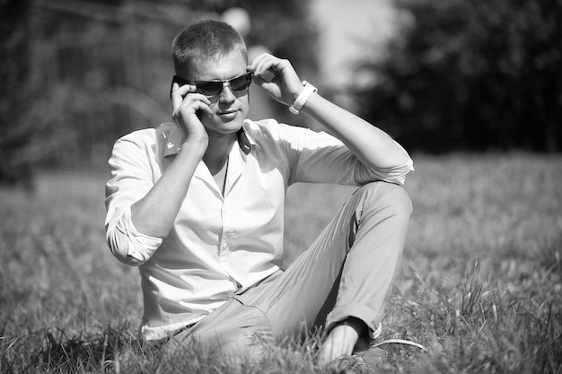 Schöner Macho genießt Sommertag Geschäftsmann mit Sonnenbrille im sonnigen Außenbereich Mann entspannt sich auf grünem Gras Modestil und Trend Break Time Konzept
