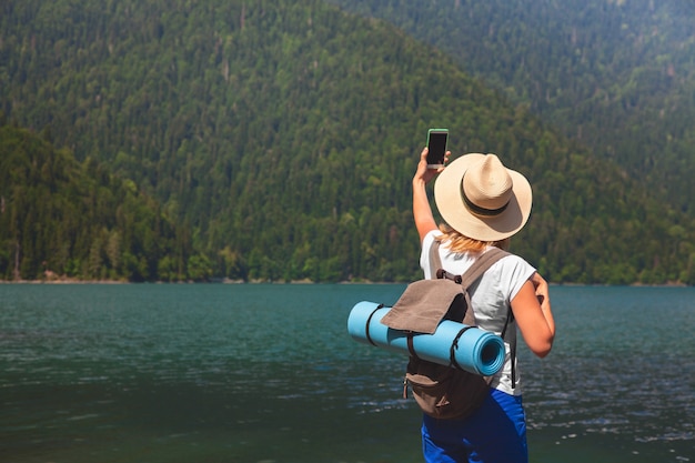 Schöner Mädchen-Reisender macht selfie auf einem großen blauen Gebirgssee im Hintergrund der Berge