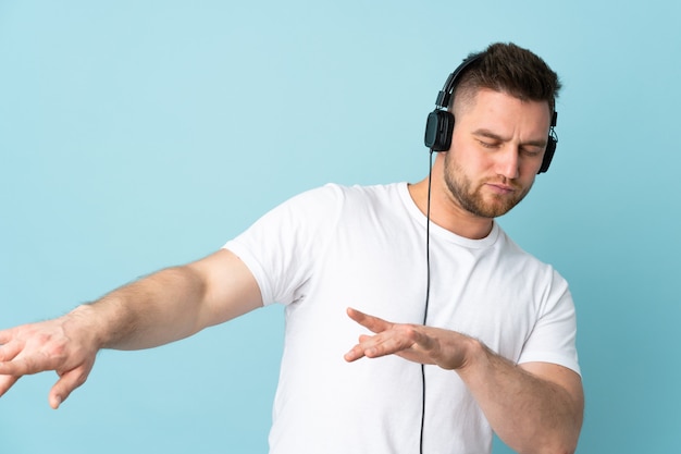 schöner Mann an der blauen Wand, der Musik hört und tanzt