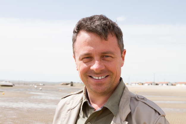 Schöner Mann, der am Strand in die Kamera lächelt