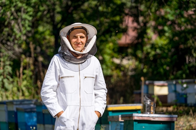 Schöner Mann, der Bienenzucht mit Bienenstock betreibt Bienenwachs im sonnigen Sommer ernten