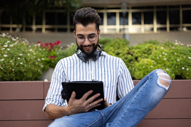 Schöner Mann, der sein Tablet auf einer Bank überprüft