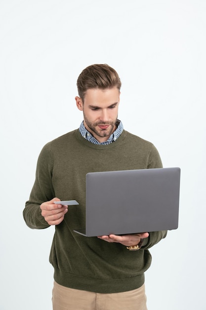 Schöner Mann Geschäftsmann hält Kreditkarte und Laptop für die Online-Zahlung isoliert auf weißem Online-Shopping