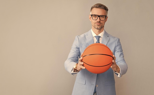 Schöner Mann hält Basketballball auf grauem Hintergrund kopieren Raumgeschäft