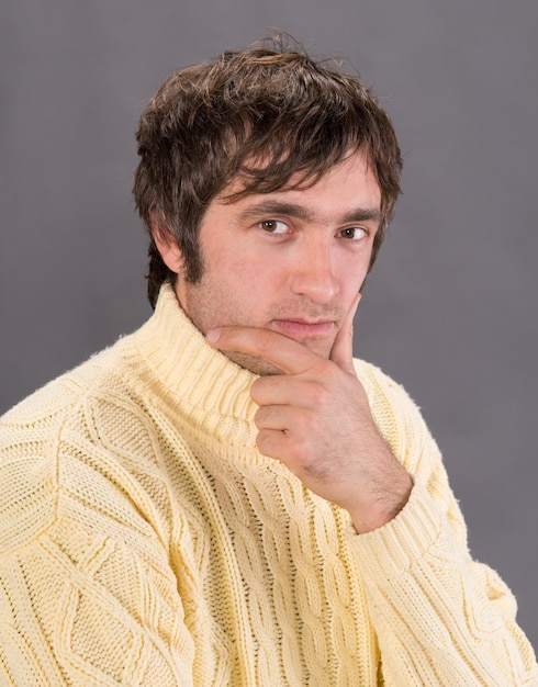 Schöner Mann im Pullover auf grauem Hintergrund posieren