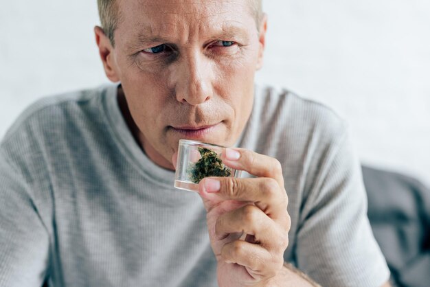 Schöner Mann im T-Shirt, der medizinisches Cannabis in der Wohnung riecht