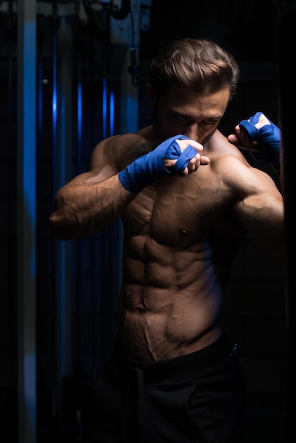 Schöner Mann in blauen Boxhandschuhen Boxen im Fitnessstudio das Konzept eines gesunden Lebensstils die Idee für den Film über das Boxen