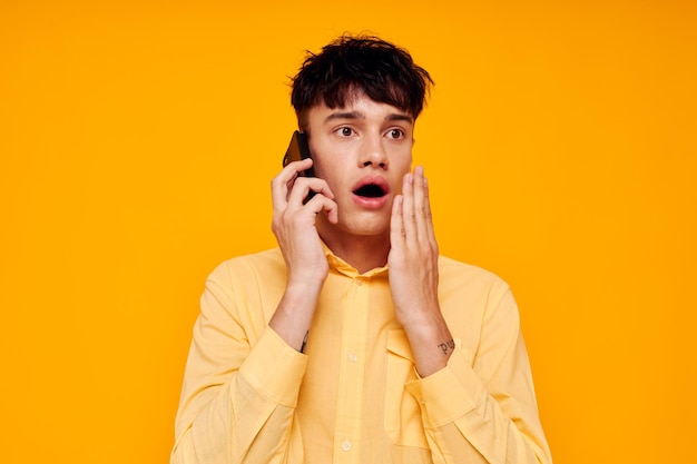 Schöner Mann in einem gelben Hemd, der am Telefon spricht, Nahaufnahme