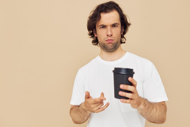 Schöner Mann in einem weißen T-Shirt mit einem schwarzen Glas in der Hand Lifestyle unverändert