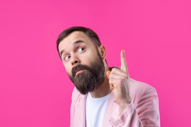Schöner Mann mit Bart in rosa Jacke denkt über einen isolierten roten Hintergrund nach