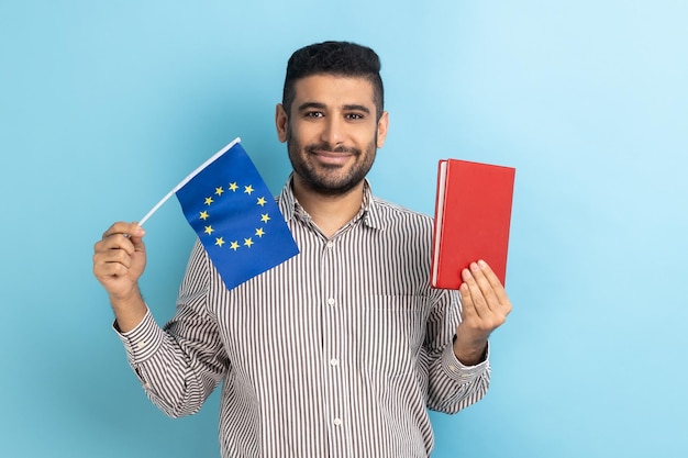 Schöner Mann mit Buch und EU-Flaggenbildung im Ausland, der in die Kamera schaut