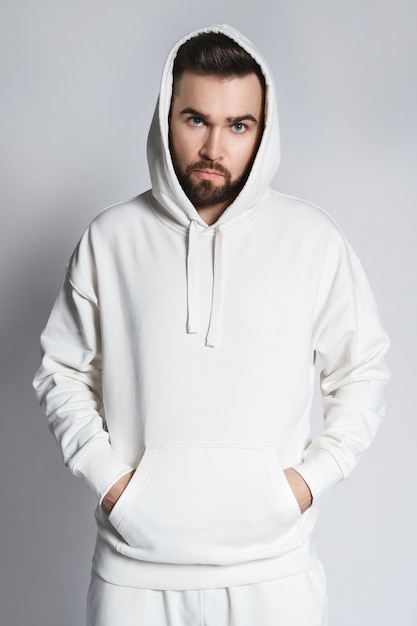 Schöner Mann mit leerem weißen Hoodie und Hose