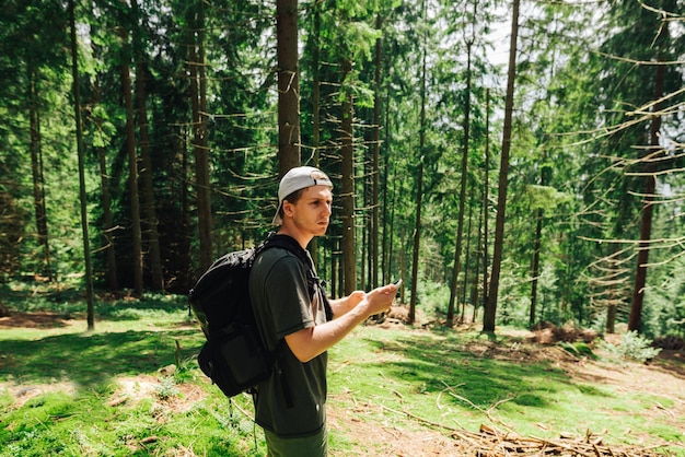 Schöner Mann mit Rucksack und lässigen Spaziergängen durch den Bergwald