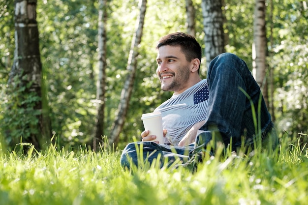 Schöner Mann trinkt Kaffee im Park