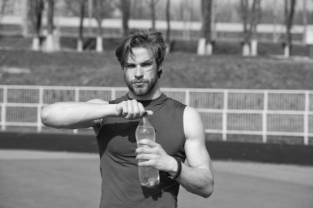 Schöner muskulöser Mann hält Wasserflasche