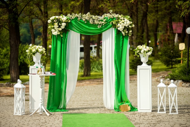 Schöner Platz für die Hochzeit mit dem Bogen verziert mit Blumen im Park.