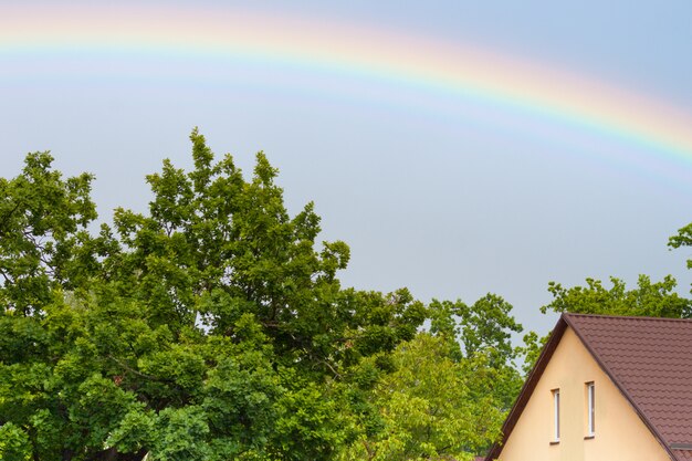 Schöner Regenbogen über den Dächern, Haus im Sommer.