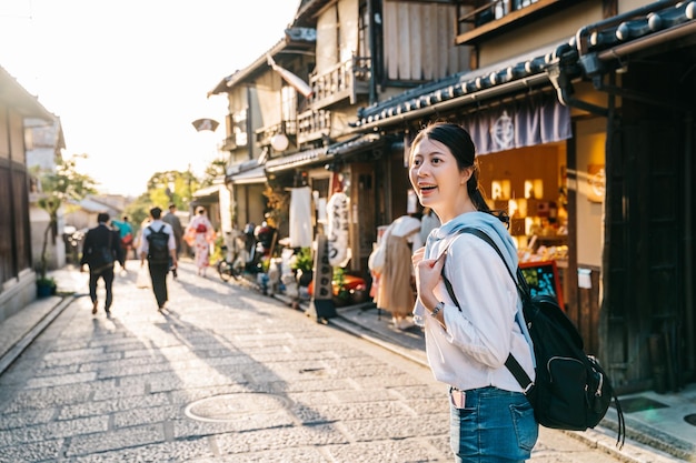 Schöner Reisender, der auf der traditionellen japanischen Straße steht und den besonderen Laden anlächelt. Seltsamerweise reisen junge Rucksacktouristen alleine durch Japan. Genießen Sie den japanischen Lebensstil.