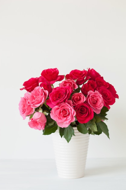 Schöner roter Rosenblumenstrauß in der Vase über Weiß