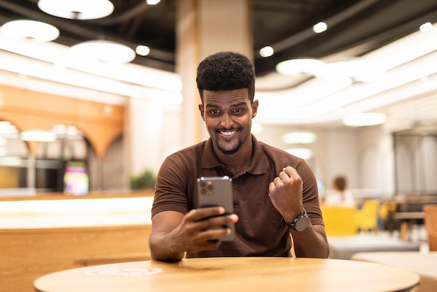 Schöner schwarzer Mann im Café mit Handy