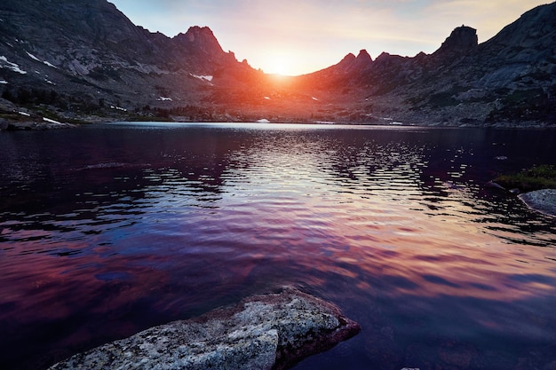 Schöner See in den Bergen in der Abendsonne. Sonnenuntergang in den fabelhaften Bergen, der See, der durch einen Steineinsturz gebildet wurde. Frühling in den Bergen