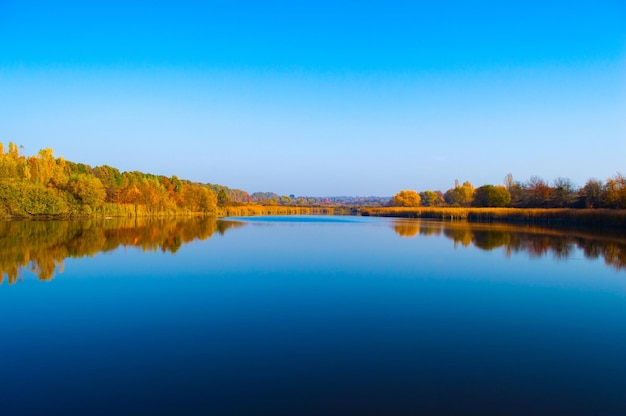 Schöner See mit Reflexion des blauen Himmels und Herbstbäume