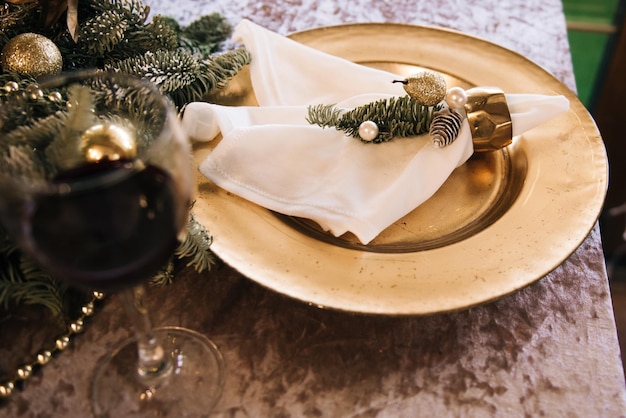 Schöner Serviertisch mit goldenen Tellern, dekoriert mit Fichte Das Konzept von Weihnachten