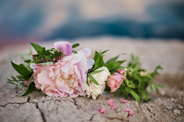 Schöner Sommerblumenstrauß von Rosen liegt auf dem gebrochenen Boden