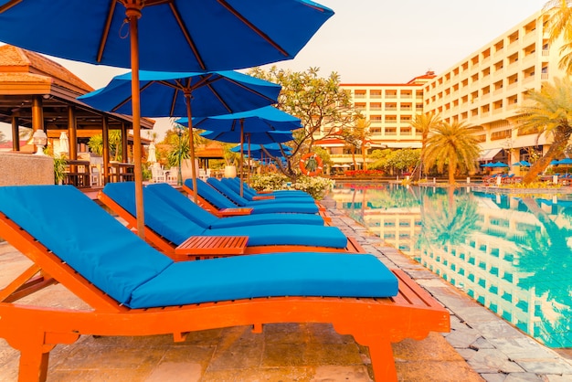 Schöner Sonnenschirm und Stuhl rund um den Pool im Hotel und Resort