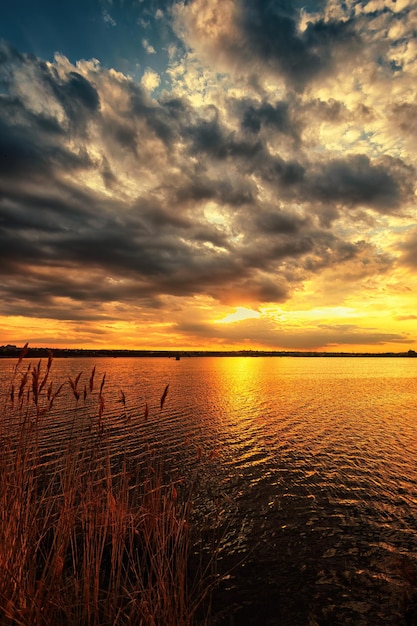 Schöner Sonnenuntergang am Seeufer mit dramatischem Himmel und Wolken