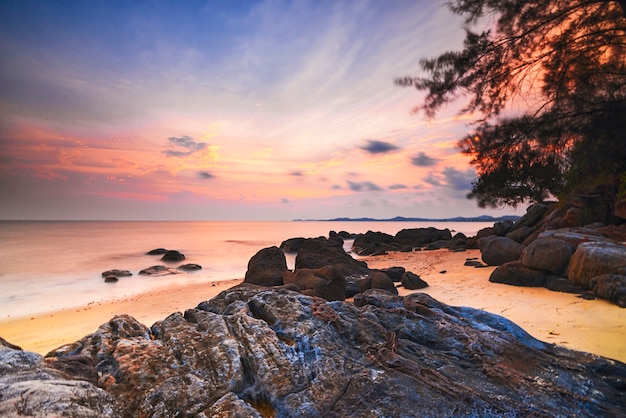 schöner Sonnenuntergang am Strand mit Felsen entlang der Küste