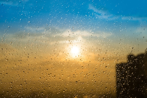 Schöner Sonnenuntergang durch ein bespritztes Glas mit Wasserregentropfen