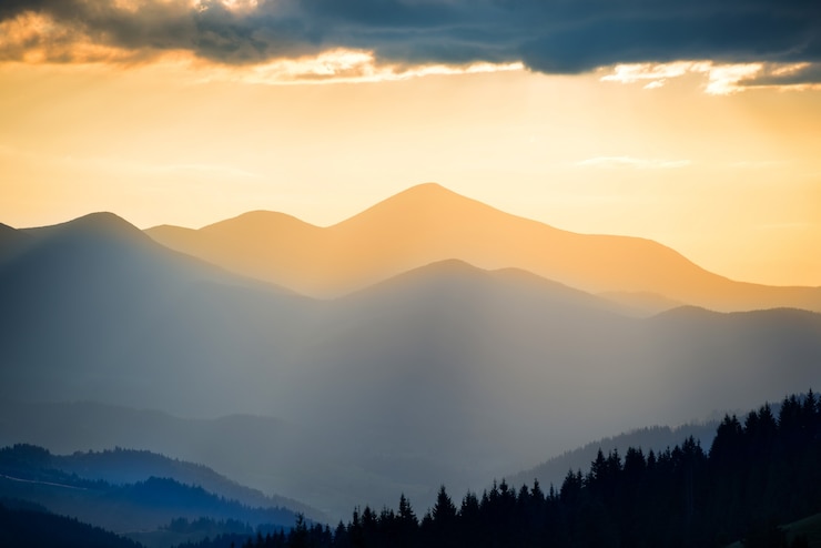 Foto schöner sonnenuntergang in den bergen. landschaft mit sonne, die durch orangefarbene wolken scheint