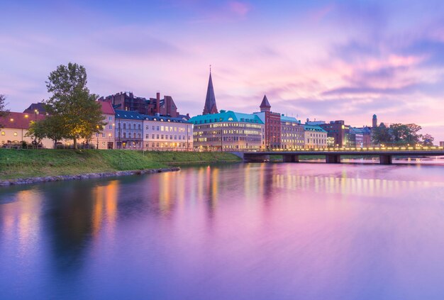 Schöner Sonnenuntergang in Malmö, Schweden. Malerischer Blick auf eine alte europäische Stadt am Abend. Skyline spiegelt sich im Wasser. Fotografie mit Langzeitbelichtung