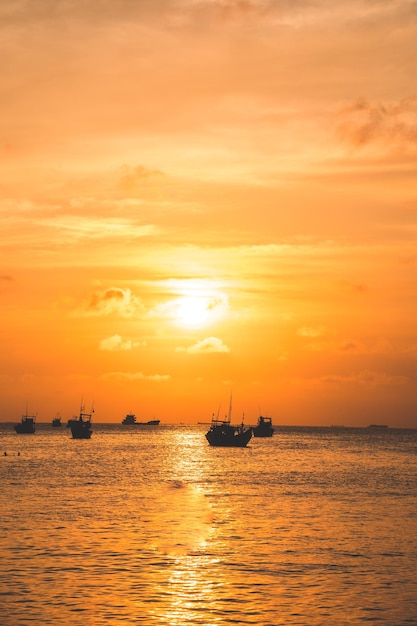 Schöner Sonnenuntergang Tropical Seascape mit einem Boot am Sandstrand bei Bewölkung