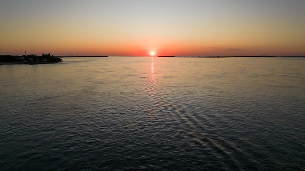 Schöner Sonnenuntergang über dem Fluss mit Booten, die im Hintergrund fischen