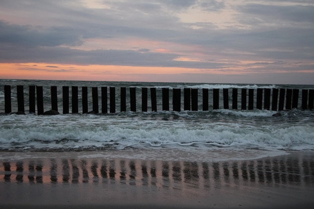 schöner Sonnenuntergang über dem Meer bei stürmischem Wetter mit roten Reflexen auf Gischt und Meeresschaum