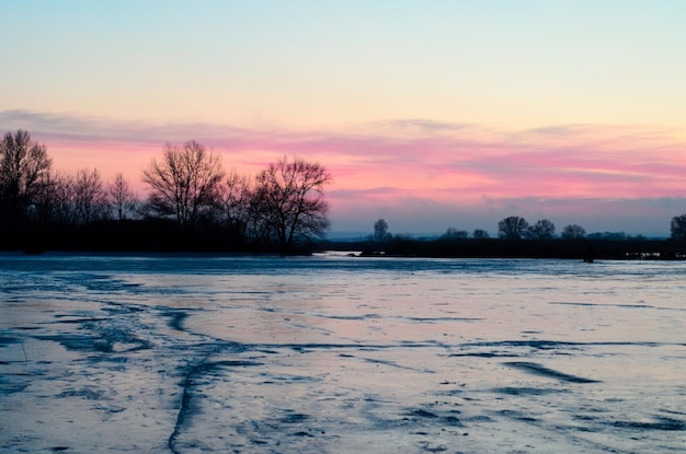 Schöner Sonnenuntergang über dem zugefrorenen Fluss