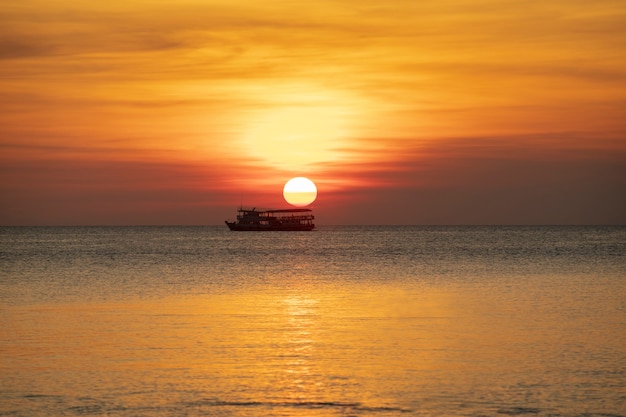 schöner Sonnenunterganghimmel in Meer horizontal mit dem einsamen Bootsschwimmen