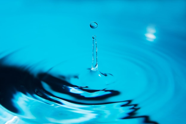 Schöner Spritzer Wassertropfen auf Wasseroberfläche in Blau