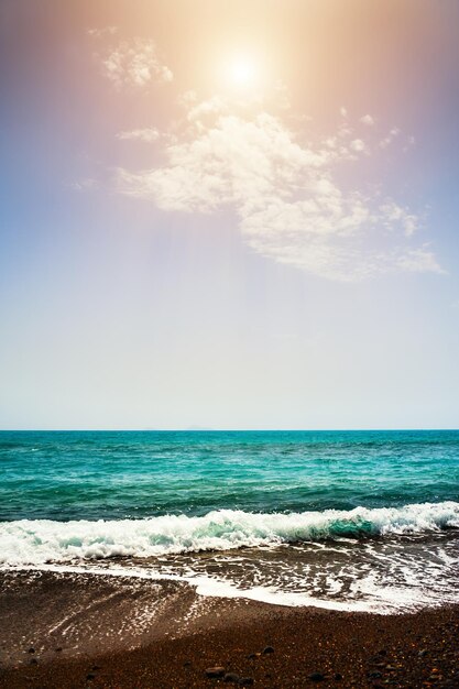 Schöner Strand mit schwarzem Sand und türkisfarbenem Meer am sonnigen Tag. Roter Strand auf der Insel Santorini, Griechenland.