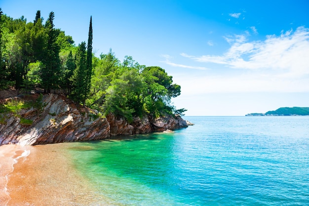 Schöner Strand mit türkisfarbenem Wasser und Klippen in der Nähe von Budva, Montenegro. Sommermeerblick, Reisen und Urlaub